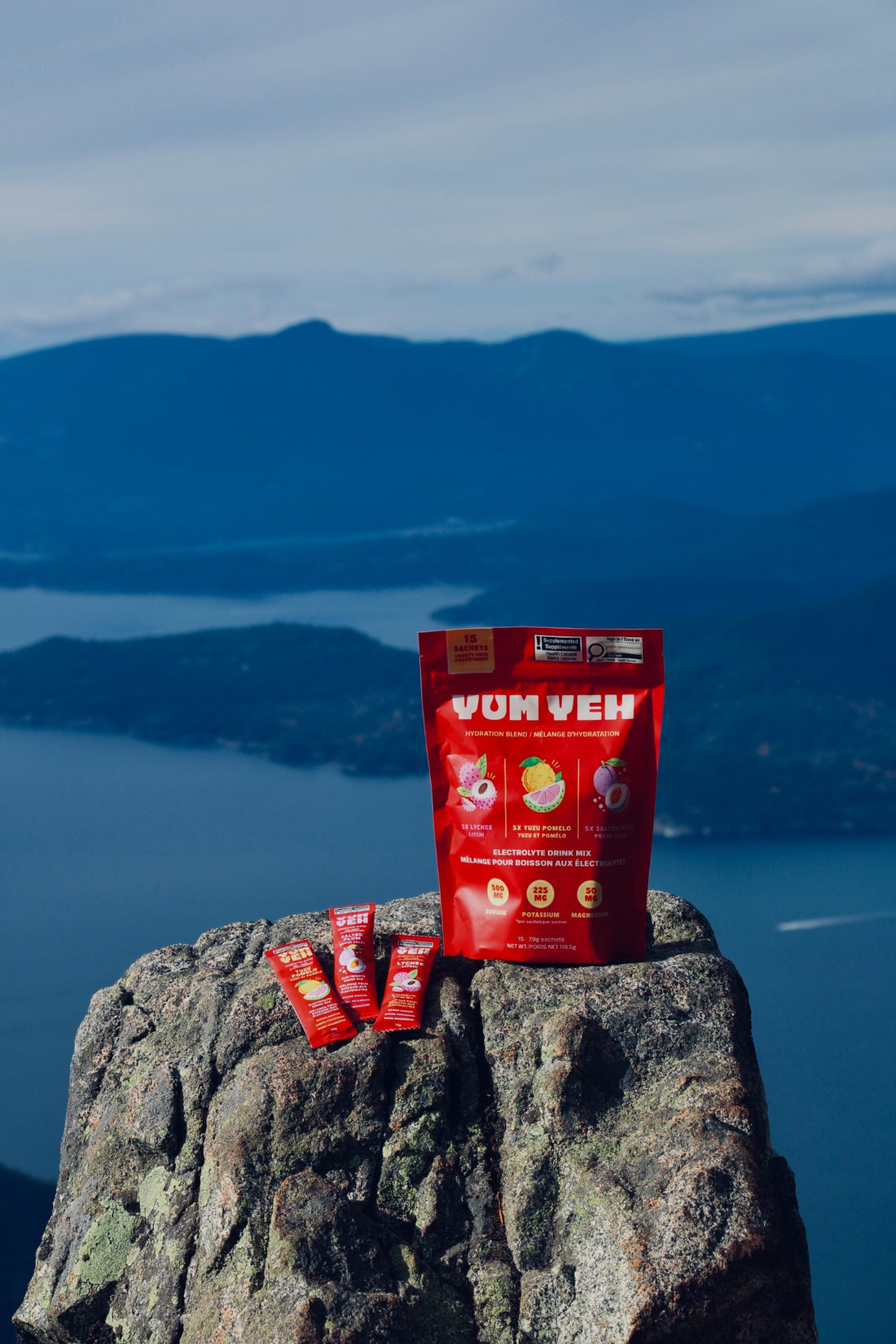 YumYeh electrolyte variety pack pouch and three stick packs on a rock summit above the ocean