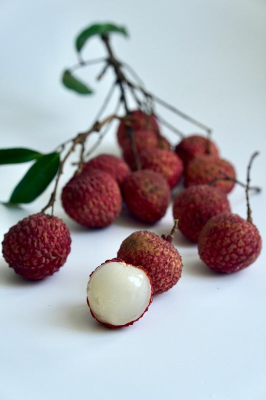 Fresh lychees, one peeled to show the white flesh